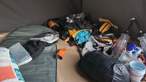A pile of jumbled kit, sleeping bags, water bottles, dry bags