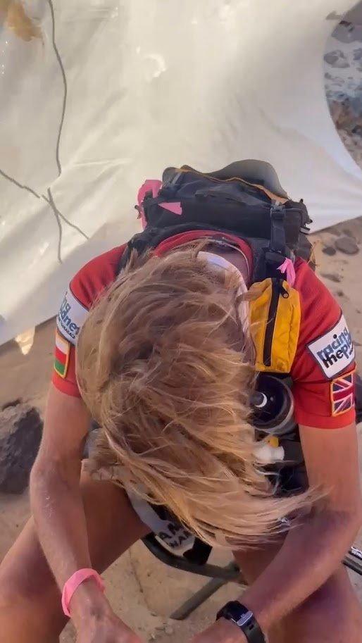 Hair blown wild over a face mid-race, head down, kit on